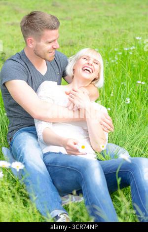 Un couple amoureux s'assoit joyeusement dans un pré avec des marguerites. Banque D'Images