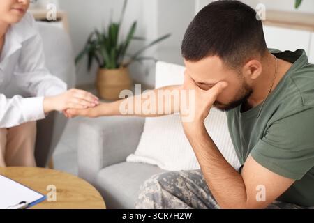 Soldat contrarié avec le TSPT et psychologue tenant la main dans le bureau, gros plan Banque D'Images