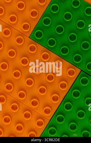 Les briques Lego orange vif et vert sont disposées sur une surface plane, invitant les enfants et les adultes à jouer et à pratiquer des activités de construction imaginatives Banque D'Images