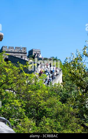 Pékin, Chine - 18 septembre 2025 : des foules de visiteurs explorent une ancienne fortification en pierre, serpentant à travers des montagnes luxuriantes sous un ciel bleu clair Banque D'Images