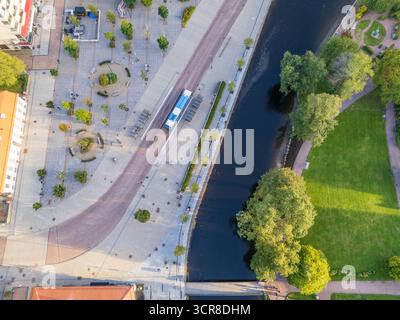 Vue aérienne de dessus d'un bus bleu sur une place de transit moderne à côté de la rivière Viskan et d'un parc vert à Borås, en Suède Banque D'Images