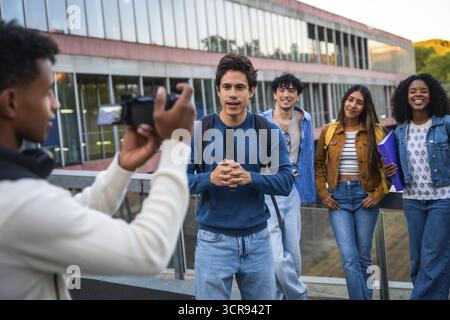 Groupe de divers étudiants universitaires collaborant, avec un étudiant tenant un microphone et parlant dans une caméra étant filmé par un autre, créant Banque D'Images
