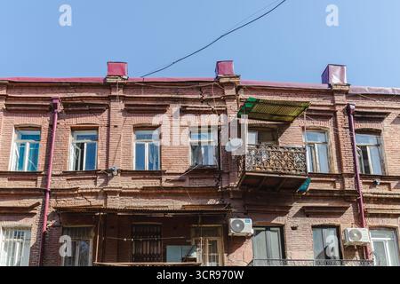 Vue sur un vieux bâtiment en brique debout avec son toit rouge et balcon orné, un aperçu du patrimoine architectural de Tbilissi, Tbilissi, Tbilissi, Géorgie. Banque D'Images