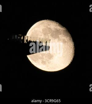 Vue aérienne de la plate-forme d'observation silhouettée grouillant de minuscules personnages sur fond d'une pleine lune dramatiquement grande et lumineuse, The Edge, New York, USA Banque D'Images