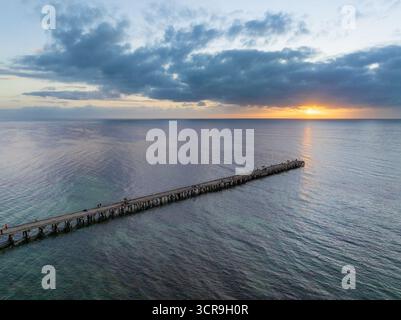 Vue aérienne du lever du soleil sur un océan calme au bout d'une longue jetée étroite à Ardrossan sur la péninsule de Yorke en Australie méridionale. Banque D'Images