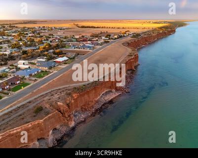Vue aérienne d'or ; la lumière se lavant sur la terre autour d'un twonship côtier perché sur les hautes falaises océaniques à Ardrossan sur la péninsule de Yorke dans South Aust Banque D'Images