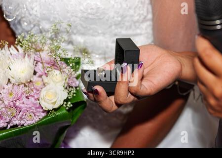 bague de mariage de mariée africaine en gros plan, robe et fleurs, main avec manucure tenant la boîte, Banque D'Images
