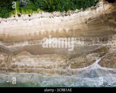 Vue de dessus des marées et des vagues sur une plage de sable à côté d'une forêt tropicale Banque D'Images