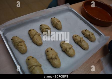 Figures de pâte crétoise Lazarakia non cuites levant sur du papier parchemin, prêtes pour le four. Préparation du Carême avant la fête de la résurrection. Banque D'Images