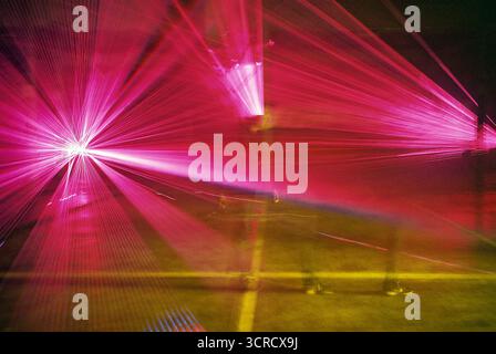 Photo de film analogique de faisceaux lumineux rouges et violets coupant à travers la brume dans un ensemble de garage. Les lasers s'étendent vers la caméra - surréaliste, graveleux, atmosphérique. Banque D'Images