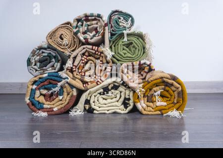 Des tapis colorés, pliés en rouleaux, reposent sur le sol près du mur de la pièce. Banque D'Images