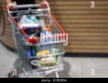 gros plan flou d'un panier complet avec de l'eau, des œufs et des boissons gazeuses. représente la consommation, le consumérisme, le shopping familial et le dai Banque D'Images