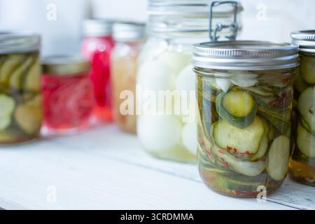 Une vue sur plusieurs bocaux mason remplis d'une variété de légumes marinés, avec du concombre et des œufs. Banque D'Images