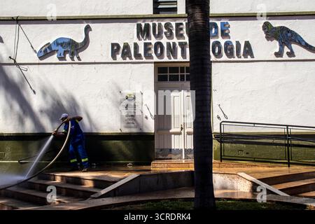Marilia, SP, Brésil, 10 septembre 2025. Travailleur lavant le trottoir avec un tuyau devant le musée de paléontologie dans le centre-ville, soulignant ur Banque D'Images