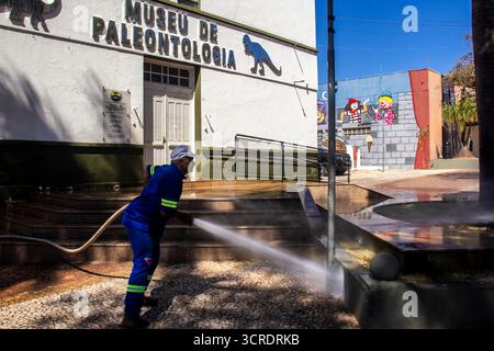 Marilia, SP, Brésil, 10 septembre 2025. Travailleur lavant le trottoir avec un tuyau devant le musée de paléontologie dans le centre-ville, soulignant ur Banque D'Images