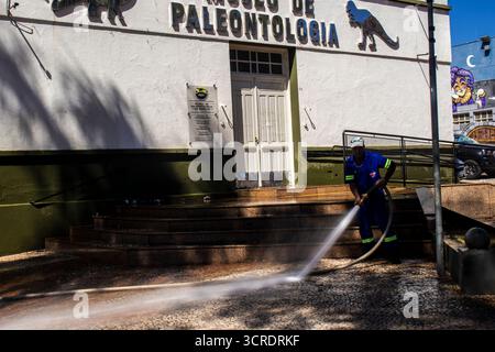 Marilia, SP, Brésil, 10 septembre 2025. Travailleur lavant le trottoir avec un tuyau devant le musée de paléontologie dans le centre-ville, soulignant ur Banque D'Images
