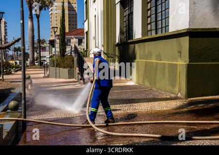 Marilia, SP, Brésil, 10 septembre 2025. Travailleur lavant le trottoir avec un tuyau devant le musée de paléontologie dans le centre-ville, soulignant ur Banque D'Images