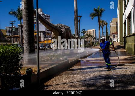 Marilia, SP, Brésil, 10 septembre 2025. Travailleur lavant le trottoir avec un tuyau devant le musée de paléontologie dans le centre-ville, soulignant ur Banque D'Images