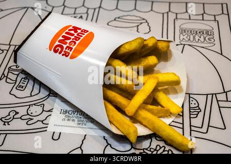 Marilia, SP, Brésil, 29 mai 2025. Frites Burger King renversées dans un sac de papier blanc sur fond de napperon illustré, mettant en valeur le son de restauration rapide Banque D'Images