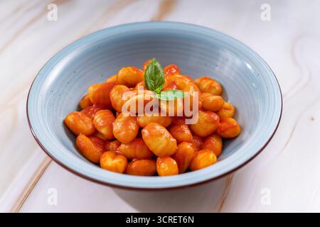 Gnocchi dans un bol bleu avec une riche sauce tomate et une feuille de basilic frais Banque D'Images