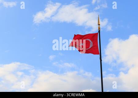 Un drapeau turc agite sur un fond de ciel nuageux et bleu Banque D'Images