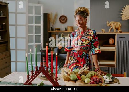 Portrait de jeune femme noire adulte célébrant Kwanzaa avec table de fête Banque D'Images