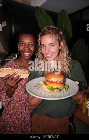 Diverses femmes amies appréciant les hamburgers fast food hot-dogs Banque D'Images