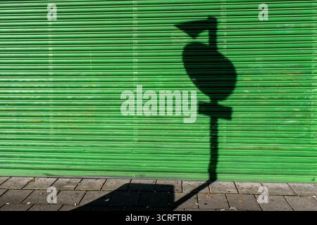 Ombre du panneau de signalisation sur l'obturateur vert fermé de la boutique Banque D'Images
