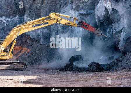 Une pelle sur chenilles KOMATSU PC490 LC équipée d’un marteau hydraulique (marteau à percussion) séparant la roche basaltique volcanique dans une carrière sur l’Etna Banque D'Images
