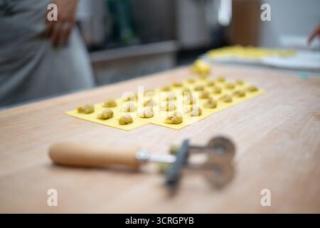 Pâte de remplissage à base de raviolis fraîche et artisanale soigneusement préparée sur un moule jaune prêt pour la cuisson Banque D'Images