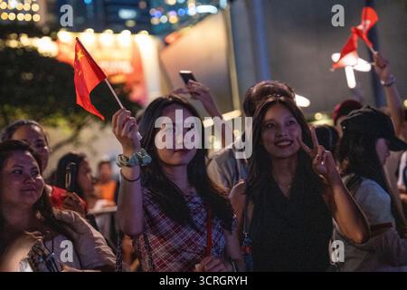 Hong Kong, Hong Kong. 1er octobre 2025. Deux femmes brandissent un drapeau de jour national chinois avant le feu d'artifice de la fête nationale chinoise le 1er octobre 2025 à Hong Kong. (Photo de Vernon Yuen/Nexpher images) crédit : Nexpher images Limited/Alamy Live News Banque D'Images