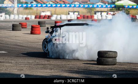 Voiture dérivant sur la piste avec beaucoup de fumée de pneus brûlants Banque D'Images