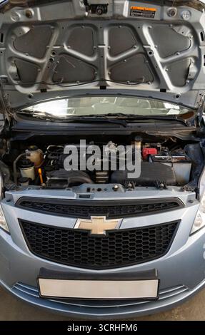 Vue avant d'une voiture Chevrolet avec capot ouvert montrant le compartiment moteur, les composants et la batterie. Concept de réparation automobile, d'entretien et d'inspection Banque D'Images