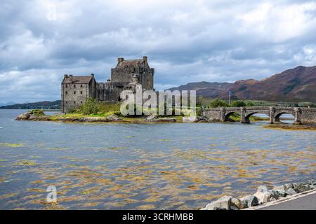 Un château médiéval escarpé se trouve sur un îlot rocheux, entouré d'une eau bleue calme et de collines lointaines. Cette forteresse intemporelle évoque l'histoire, scénographe maritime Banque D'Images