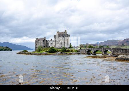 Un château médiéval escarpé se trouve sur un îlot rocheux, entouré d'une eau bleue calme et de collines lointaines. Cette forteresse intemporelle évoque l'histoire, scénographe maritime Banque D'Images