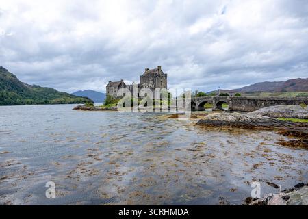 Un château médiéval escarpé se trouve sur un îlot rocheux, entouré d'une eau bleue calme et de collines lointaines. Cette forteresse intemporelle évoque l'histoire, scénographe maritime Banque D'Images