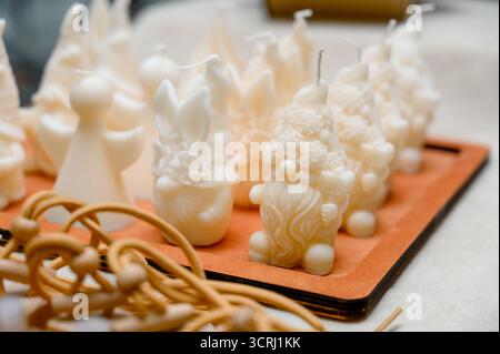 Un ensemble de bougies blanches faites à la main en forme de gnomes, lapins et anges. Un assortiment de bougies blanches en forme de personnages de conte de fées sur th Banque D'Images