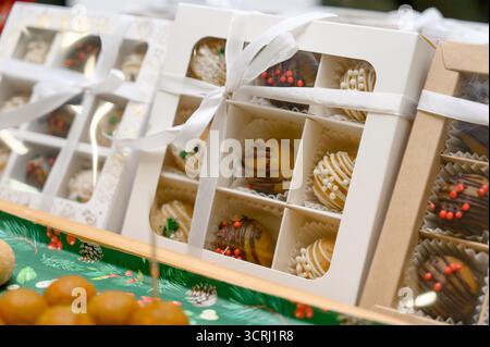 Une sélection de chocolats faits à la main dans des coffrets cadeaux. Gros plan d'un coffret cadeau contenant des gâteaux nappés de chocolat et des saupoudrés de couleurs vives Banque D'Images