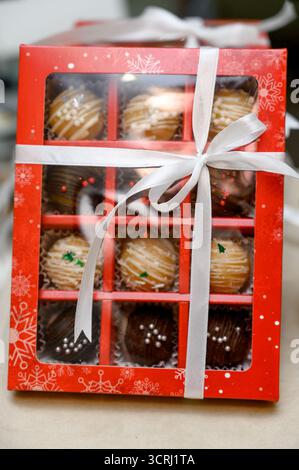 Une sélection de chocolats faits à la main dans des coffrets cadeaux. Gros plan d'un coffret cadeau contenant des gâteaux nappés de chocolat et des saupoudrés de couleurs vives Banque D'Images