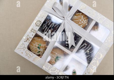 Une sélection de chocolats faits à la main dans des coffrets cadeaux. Gros plan d'un coffret cadeau contenant des gâteaux nappés de chocolat et des saupoudrés de couleurs vives Banque D'Images