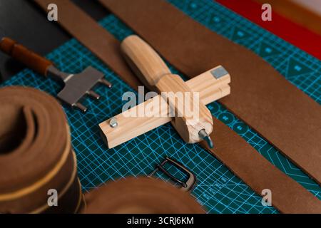 Installation de travail du cuir avec des outils, une boucle et des bandes de cuir disposées soigneusement sur un tapis, prêt pour la fabrication de ceinture. Outils de maroquinerie et fabrication de courroies p Banque D'Images