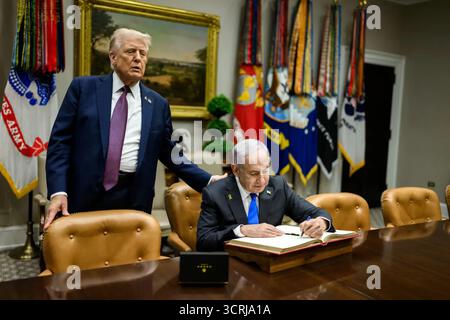 Le premier ministre israélien Benjamin Netanyahu signe le livre d’or alors que le président américain Donald Trump regarde avant leur conférence de presse conjointe annonçant le plan de paix américain pour Gaza, intitulé « Pathways to Peace : Gaza 2030 ». 29 septembre 2025. Image reproduite avec l'aimable autorisation de la Maison Blanche. Banque D'Images