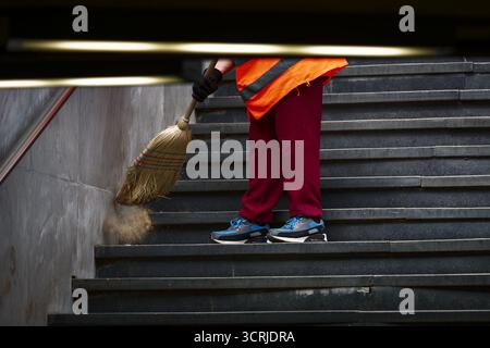 Le nettoyeur de rue balaie les escaliers dans le passage souterrain Banque D'Images