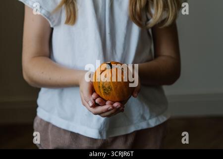 Gros plan des mains de la fille tenant une citrouille blanche décorative Banque D'Images