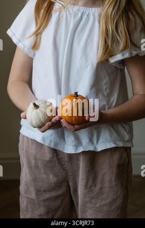 Gros plan des mains de la fille tenant une citrouille blanche décorative Banque D'Images