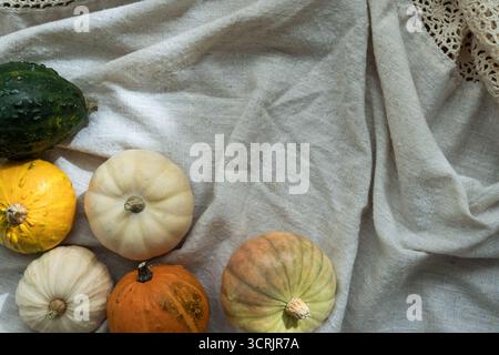 Citrouilles décoratives colorées sur tissu de lin, vue de dessus. Esthétique automnale Banque D'Images