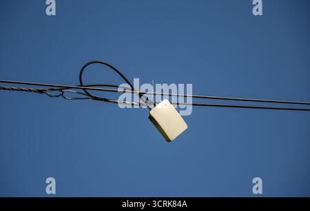 pièce d'équipement, probablement un transformateur ou un dispositif similaire, attachée à des lignes électriques. Ces lignes sont supportées par des poteaux électriques, routeur Banque D'Images