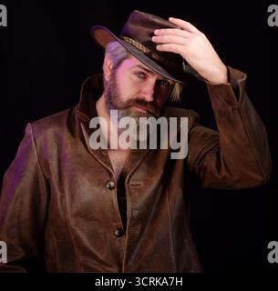 Style cow-boy. Portrait d'un bel homme barbu en chapeau de cow-boy et manteau en cuir. Cow-boy américain. Mode homme dans le style occidental. Macho barbu brutal Banque D'Images
