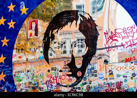Portrait stylisé de John Lennon dans un cadre circulaire, couvert de graffitis colorés et de messages sur le mur de John Lennon à Prague, République tchèque Banque D'Images