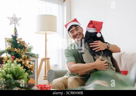 Noël couple heureux embrasse, montrant l'amour dans la maison d'hiver confortable, portant des chapeaux de père noël, célébrant Banque D'Images